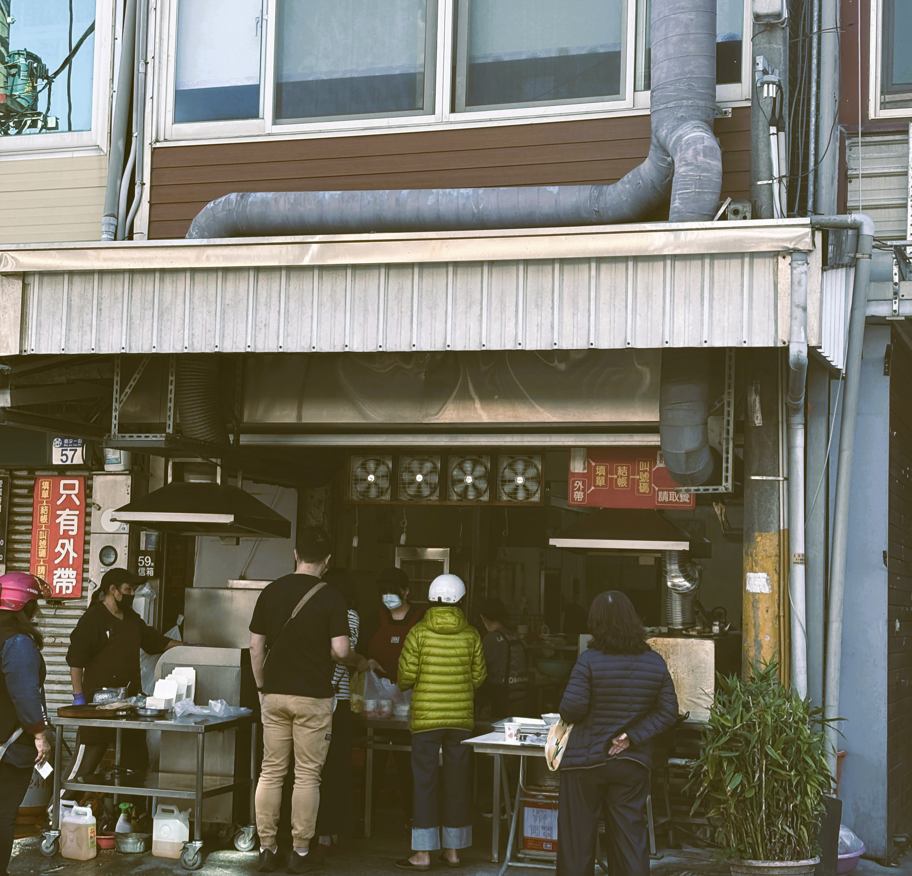 無名早餐店店面，顧客在騎樓下排隊等候購買早餐